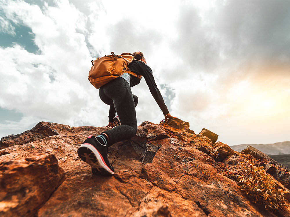 Veduta posteriore di una donna in abbigliamento sportivo che scala una roccia