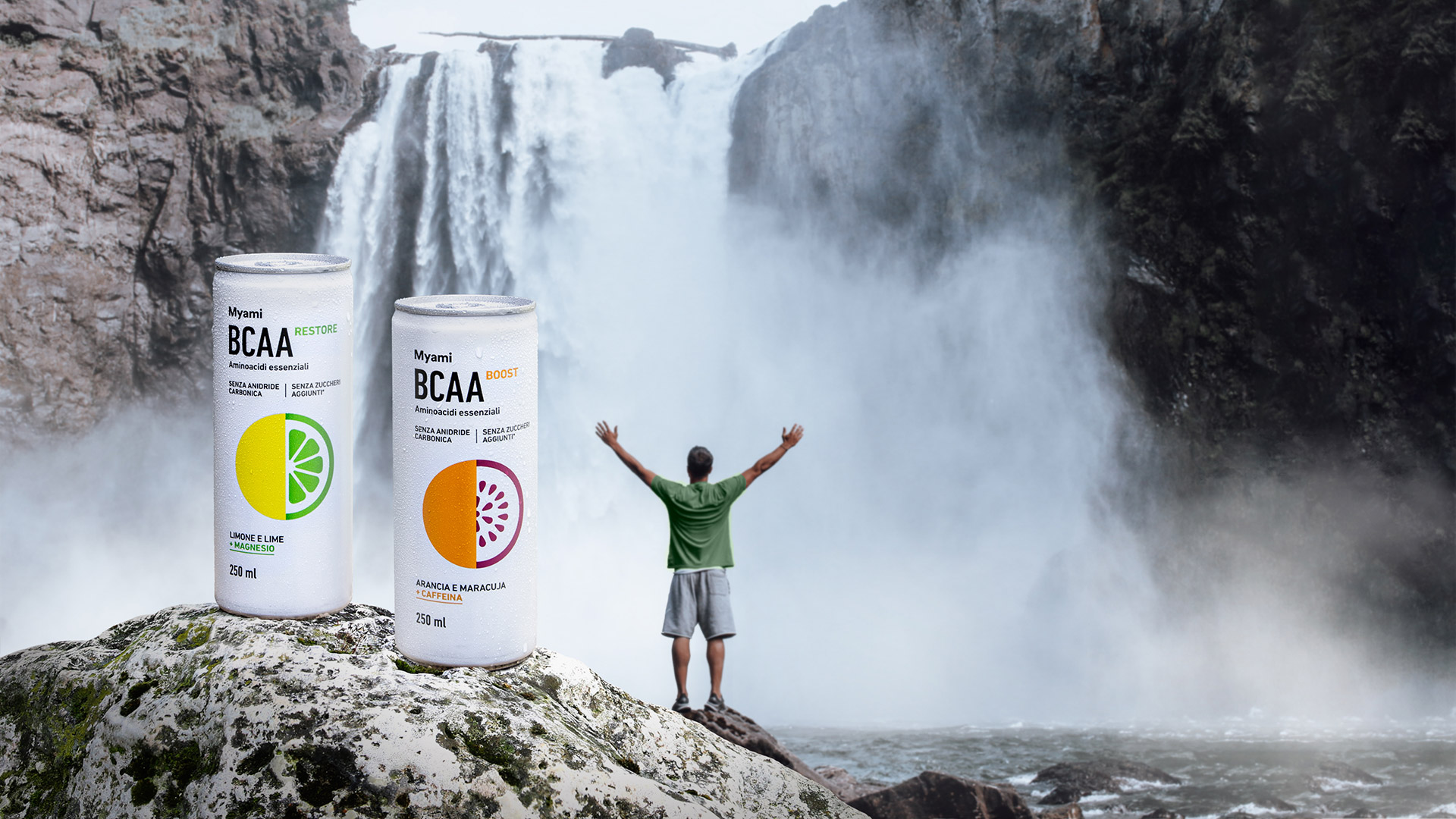 Due lattine di bevanda BCAA in primo piano, sullo sfondo un uomo che allarga le braccia di fronte a una cascata