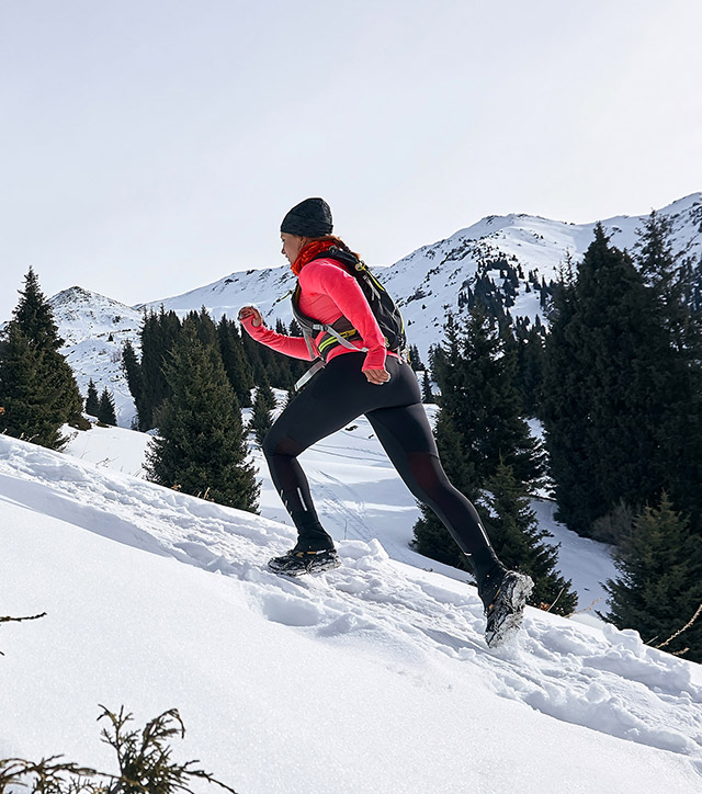 Donna in abbigliamento sportivo che scala una montagna in un paesaggio innevato