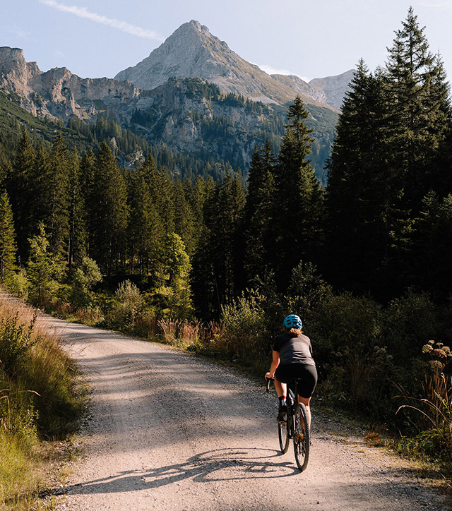 Persona con casco in bicicletta in un paesaggio di montagna